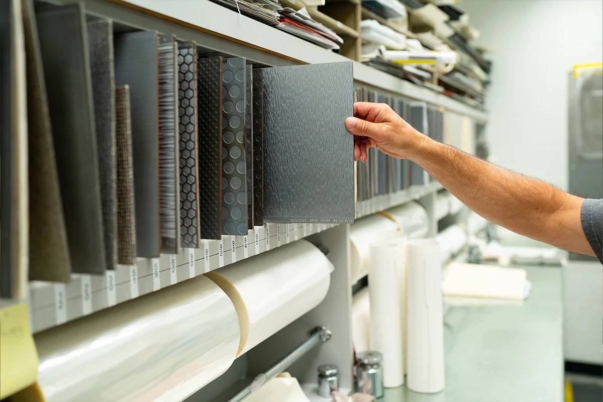 schneller-employee-arm-pulling-aircraft-flooring-swatch-out-of-cabinet-filled-with-various-swatch-designs